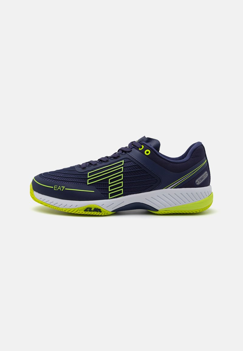 Sapatilha desportiva azul-marinho com parte superior de malha texturizada, detalhes em verde fluorescente e sola branca, apresentando um design moderno e uma estrutura de suporte.