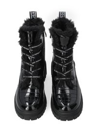 Black patent leather boots with faux fur lining, chunky sole, and decorative text on laces. High-top design with pull tab for easy wear.