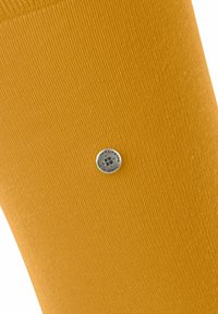 Chaussette jaune en matériau côtes, présentant un accent logo circulaire argenté près du bas, avec une texture lisse.