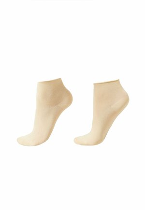 Paire de chaussettes beige à hauteur de cheville présentée sur des formes en forme de pied sur fond blanc.