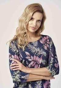 Kwiatowy top z ciemnoniebieskim tłem, wzorem różowych i zielonych liści, okrągłym dekoltem i rękawami do połowy przedramienia. Miękka tekstura tkaniny.