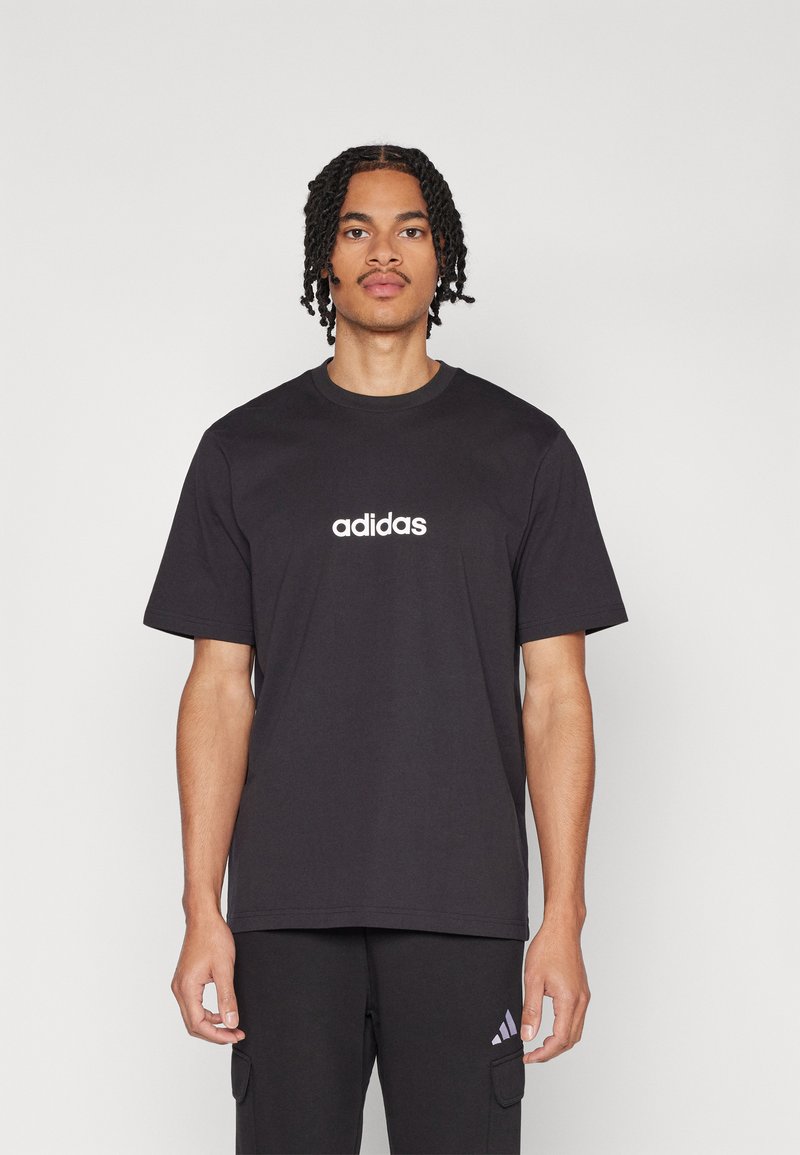 Juodas medvilninis marškinėliai trumpomis rankovėmis, su balta "adidas" logo centre. Paprastas, klasikinis kirpimas su apvaliu iškirpimu.