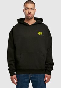 Felpa nera con tasca frontale, caratterizzata da un logo agrumato verde sul lato sinistro del petto. Realizzata in materiale morbido, con una vestibilità comoda e cappuccio con coulisse.
