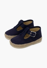 Navy blue canvas shoes with T-strap design, buckle detail, and natural jute rope sole. Flat, rounded toe and soft interior lining.