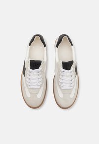 Sneaker mit einem Obermaterial aus weißem und grauem Wildleder, schwarzen Akzenten, weißen Schnüren und einer beigefarbenen Gummisohle; verfügt über eine "SUPER SOFT" Innensohle.