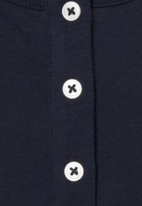 Marinblå bomullsskjorta med en knappslå med fyra vita knappar, var och en med ett centralt svart korsmönster och en slät yta.