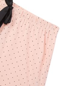 Pantaloni corti con vita elastica in morbido tessuto rosa chiaro con pois neri, dotati di un nastro nero per la regolazione e come dettaglio decorativo.