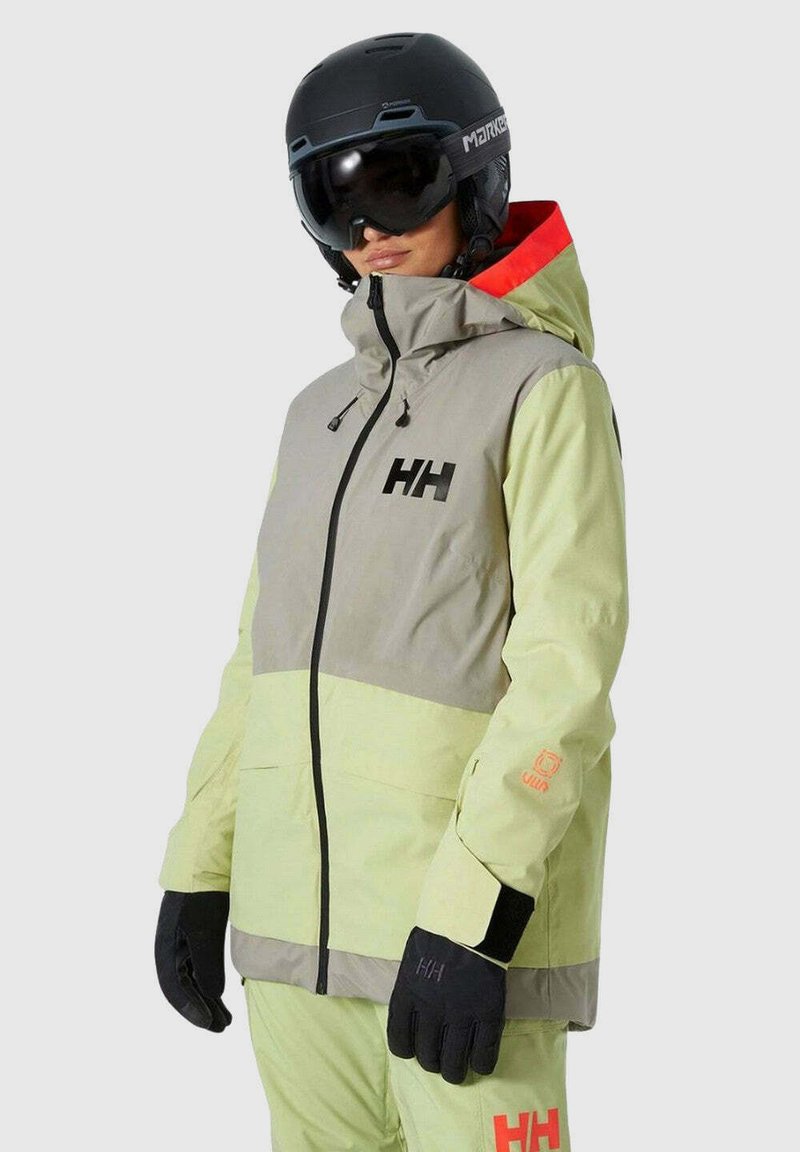 Leichte Skijacke in Grün und Grau, mit Kapuze, schwarzem Reißverschluss und Logoakzenten. Sie verfügt über elastische Bündchen und kontrastierende rote Details.