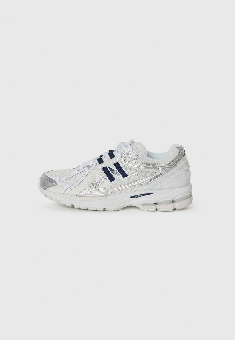 Zilveren en witte sportieve schoen met een bovenwerk van mesh, rubberen zool en marineblauwe accenten. Heeft een ronde neus en een gevoerde hiel voor ondersteuning.