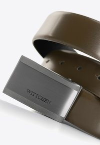 Bruine leren riem met een metallic zilveren gesp met textuur aan de randen en het gegraveerde "WITTCHEN" logo. Gaten voor verstelbare maat.