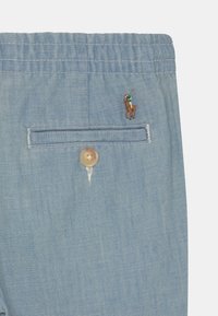 Ljusblå tygshorts med ficka med knappstängning och broderad polo-spelare-logotyp ovanför fickan på högra sidan.