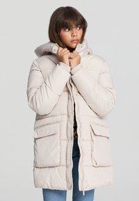 Jasnoróżowa kurtka puchowa z kapturem, z pikowanym wzorem, dużymi przednimi kieszeniami i zapięciem na zamek. Miękka tekstura i ocieplenie.