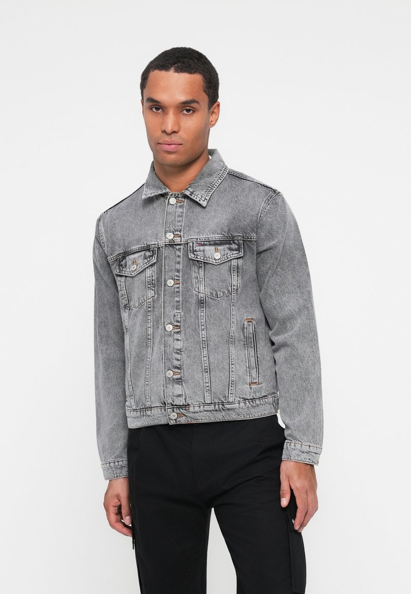 Graue Jeansjacke mit klassischem Schnitt, Knopfverschluss, zwei Brusttaschen und einer leicht ausgeblichenen Textur.