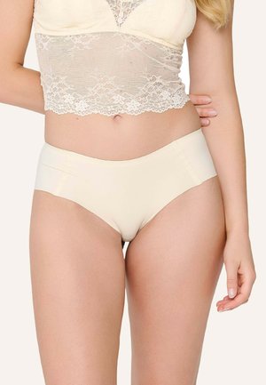 Sous-vêtements beiges sans coutures avec une texture lisse et une taille haute, complétés par un délicat bralette en dentelle au-dessus.