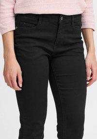 Zwart denimjeans met een slim fit, voorzien van een klassieke vijf-pocket ontwerp en een enkele knoopsluiting bij de tailleband.