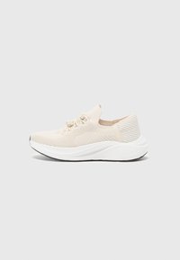 Basket de sport beige avec une tige en mesh texturé, des lacets élastiques et une semelle blanche rembourrée avec un motif sur le talon.