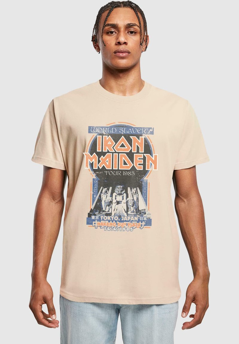 Tricou din bumbac bej, cu un print grafic al turneului Iron Maiden din 1985, cu accente albastre și portocalii și un design retro.