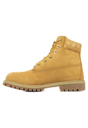 Botín de tobillo marrón de ante estilo Timberland con herrajes dorados, cuello acolchado y patrón texturizado en la parte superior. Suela de goma con relieve.