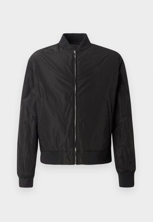 Musta bombers jope, millel on lukuga ees, soonikkoes ja hem, sujuva, läikiva tekstuur ja peenelt tikitud logo rinnal.