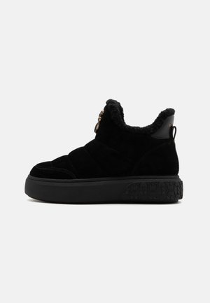 Black suede ankle boots featuring a textured platform sole, plush lining, and gold-tone hardware accent at the side.