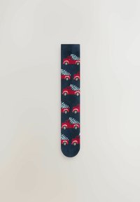 Calcetines azul marino con un patrón repetido de camiones rojos que transportan árboles de Navidad. El material parece suave con una textura lisa y puntera redondeada.