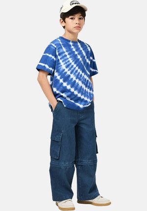 T-shirt in cotone a tinta blu tie-dye con maniche corte, abbinata a pantaloni cargo in denim scuro dalla vestibilità ampia, con tasche laterali e gamba dritta.