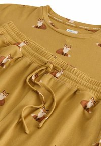 Yellow fabric top featuring a scattered fox print, with a smocked waist detail and drawstring tie. Soft texture with ribbed design.