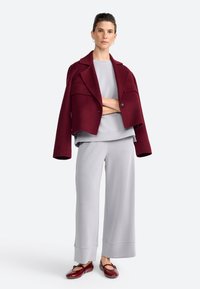 Bordeaux cropped jakke, grå lagdelt top og grå wide-leg bukser. Modellen bærer maroon ballet flats. Bløde teksturer, skræddersyet pasform, minimalistisk design.