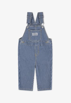 Randiga denimbyxor i blått och vitt med justerbara axelremmar, framlomme, silverfärgad hårdvara och gul sömdekor.