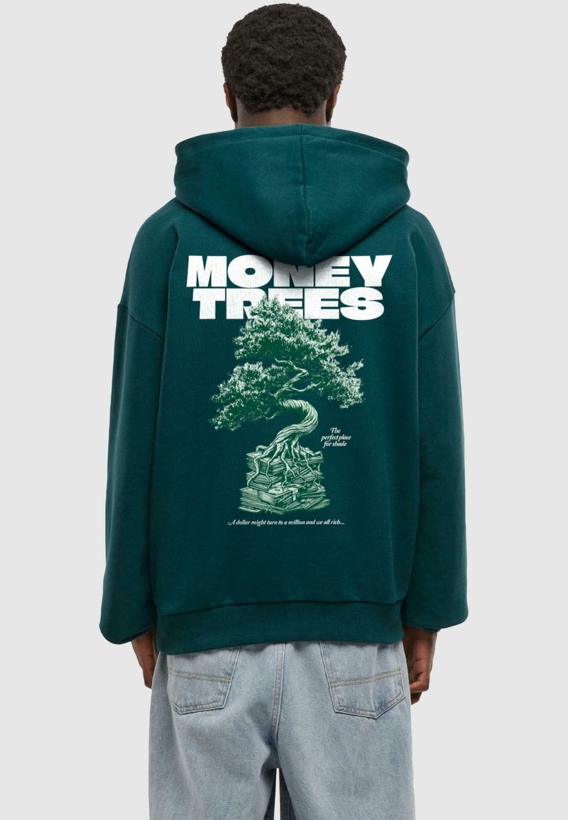 Felpa oversize verde scuro con testo bianco "MONEY TREES" e un design di un albero verde con soldi impilati alla base. Texture morbida.