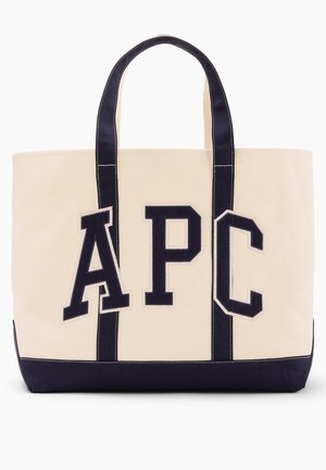 Bolsa tote de lona beige con asas y base negras, con grandes letras negras "APC" en la parte delantera.