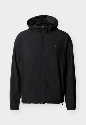 Geacă windbreaker neagră cu fermoar frontal, glugă reglabilă și manșete elastice. Prezintă un logo subtil pe piept și un material ușor.