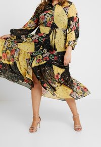 Maxime de dress ijo tilasongani ji kieti patchwork wo akhithai mklokhu mu yellow, black, nai red. Mbuyho wa phakasi mu lwangi wo tie waist. Kiyala mu chithambo.