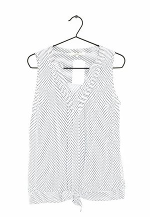 Sleeveless white blouse with black polka dots, v-neckline, and knotted hem detail. Lightweight fabric, hangs from a black hanger.