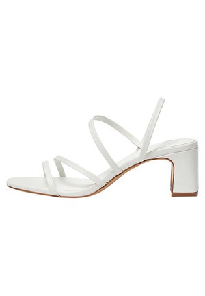 Sandale blanche à talons avec plusieurs fines lanières, un bout carré et un talon bloc sur une semelle marron clair. Le matériau semble lisse et semblable au cuir.