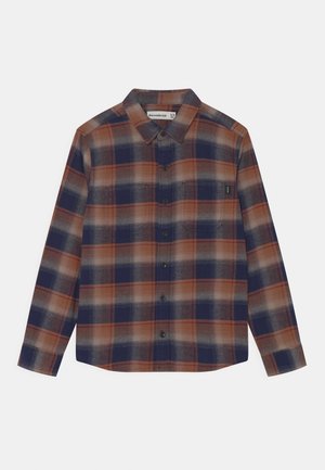 Camisa de franela de botones con mangas largas, que presenta un patrón de cuadro en marrón, marino y crema, tejido suave y botones negros.