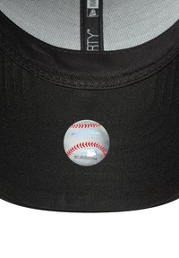 Cappellino da baseball nero con una texture in tessuto. Presenta un adesivo circolare in metallo del logo MLB sulla parte inferiore della visiera.