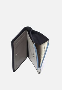 Portafoglio pieghevole in pelle blu navy. L'interno è foderato in grigio chiaro, con slot per carte e una sezione con zip blu. Accenti in metallo argentato.