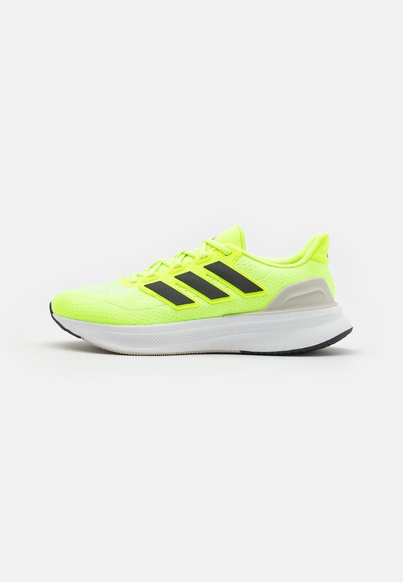Zapatillas deportivas amarillas con parte superior de malla, rayas negras y suela blanca. Presentan un talón acolchado y detalles texturizados en la parte superior.