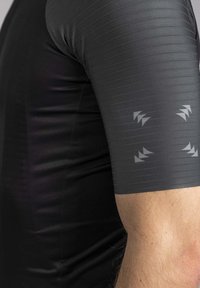 Korte mouwen, nauwsluitend zwart shirt met gestructureerde strepen, voorzien van reflecterende grijze driehoekige accenten op de schouder en mouw.