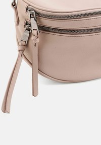 Borsa rotonda in pelle color blush con due zip argento e dettagli in pelle annodata. Presenta una superficie strutturata e un design elegante e compatto.