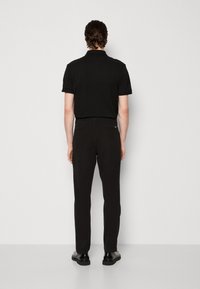 Černé polo tričko s krátkým rukávem a rovnými liniemi, spárované s černými dobře střiženými kalhotami, navržené pro přiléhavý siluetu. Hladká textura.