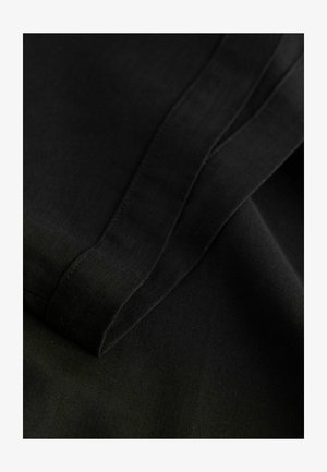 Melnas audums ar gludu tekstūru, ar salocītām malām un redzamām šuvēm. Audums ir viegls un matēts pēc izskata.