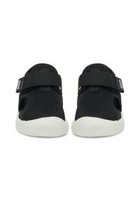 Paire de chaussures en mesh noir sans lacets avec semelles blanches et larges sangles réglables sur le dessus, vue de face.