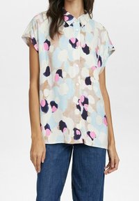 Chemise à manches courtes avec boutons, présentant un motif abstrait multicolore à pois dans des teintes pastel sur un fond clair.