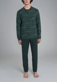 Completo pigiama verde composto da maglia a maniche lunghe con motivo a righe orizzontali e pantaloni coordinati, realizzato in tessuto morbido e testurizzato, design aderente.