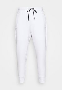 Pantalones de chándal blancos fabricados en material suave, con una cintura elástica y cordón, dos bolsillos laterales y puños ajustados.