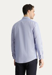 Camicia a maniche lunghe blu chiaro con sottili righe orizzontali. Presenta un colletto a punta e polsini con bottone, realizzata in un tessuto morbido.