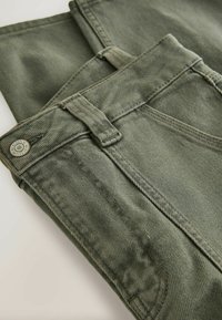 Jeans din denim verde cu un finisaj texturat, prezentând închidere cu nasture, bucle pentru curea și cusături, întinse pentru expunere.