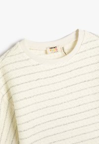 Lichtcrème trui met textuurlijnen en zilveren draad, met een ronde hals en ribgebreide cuffs. Label zichtbaar binnen in de kraag.